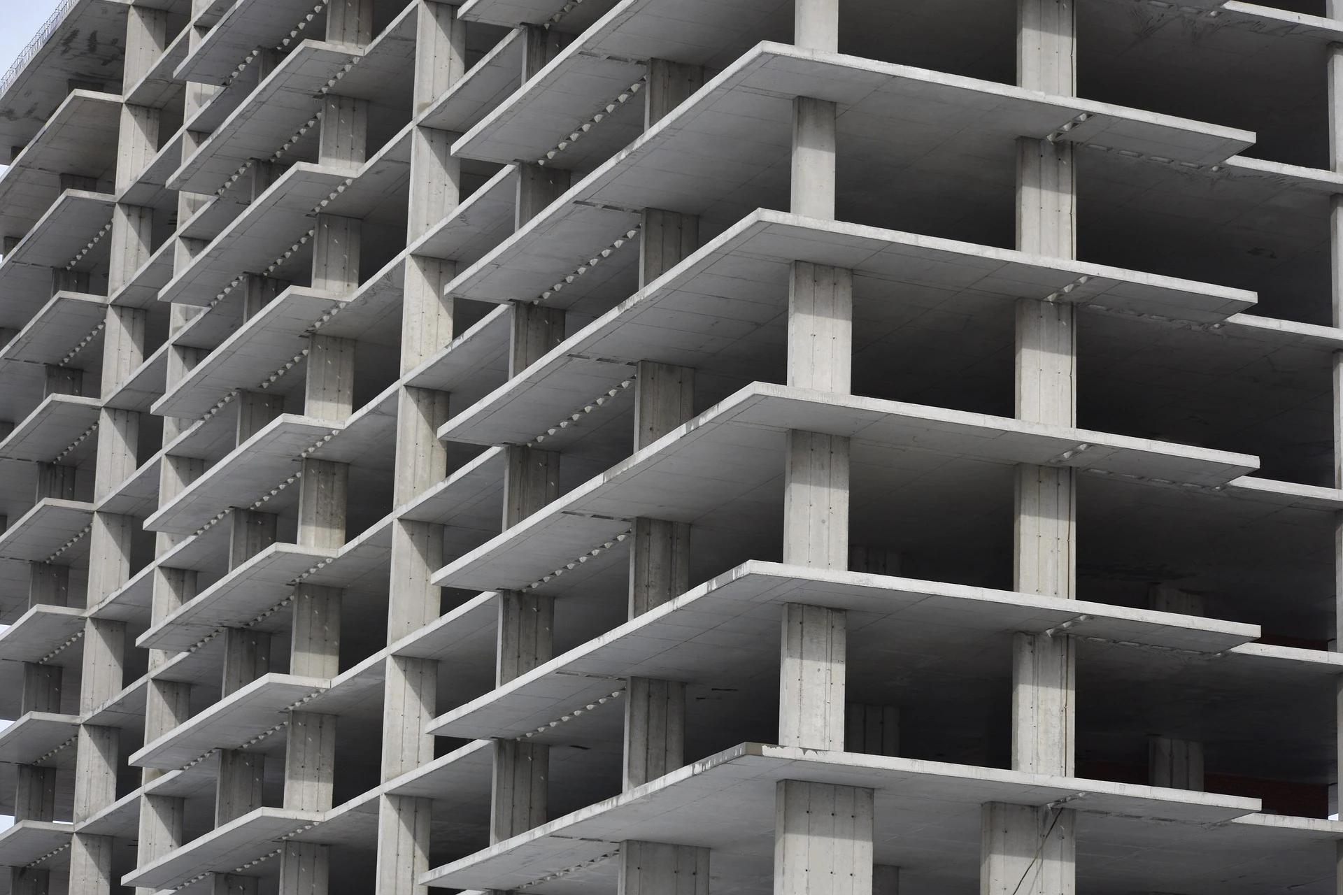 Estrutura de prédio em construção com concreto aparente, simbolizando obras, engenharia civil e construção imobiliária.